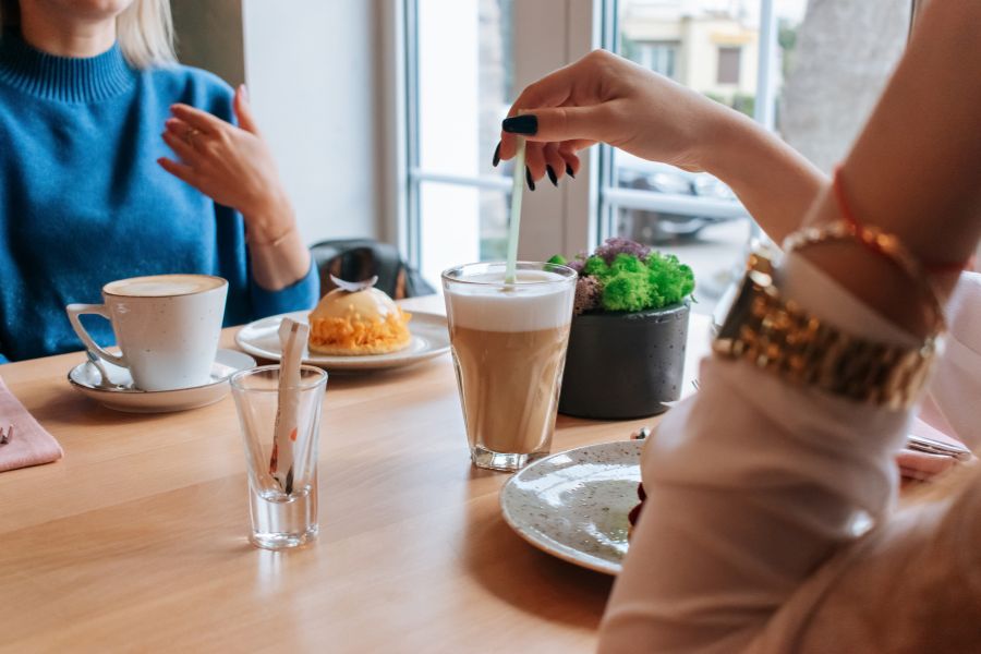 dos personas conversan mientras toman un tentempié en una cafetería
