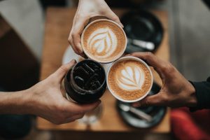 tres manos acercan sus tazas de café para hacer un brindis